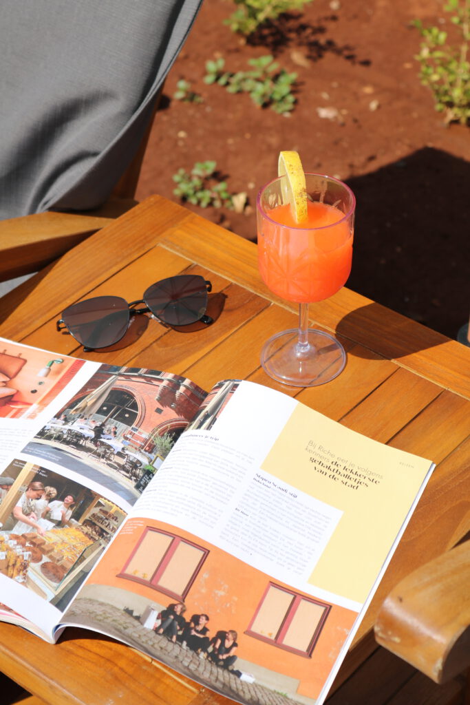 ingezoomd aperol en boekje met zonnebril op ligbedje